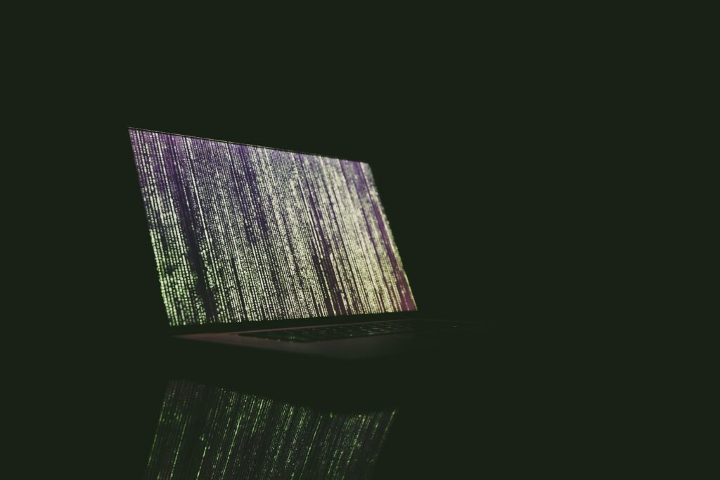Laptop displaying Matrix-like image in a dark room